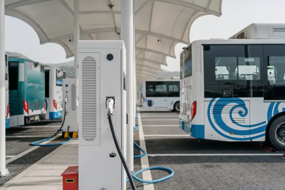White electric tranasit bus plugged into a charging station